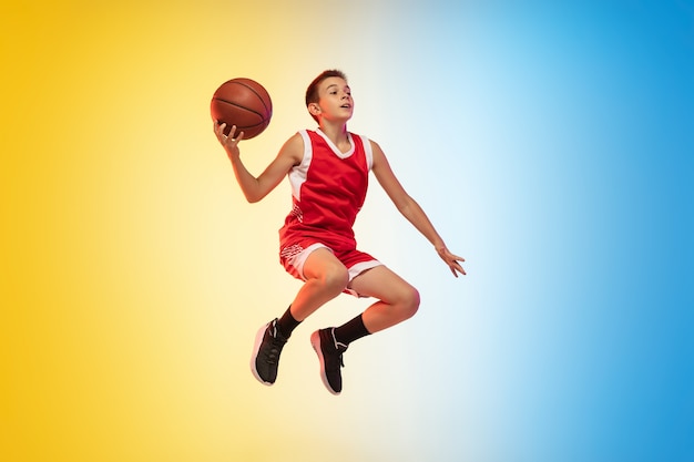 グラデーションの背景にボールを持つ若いバスケットボール選手の全身像