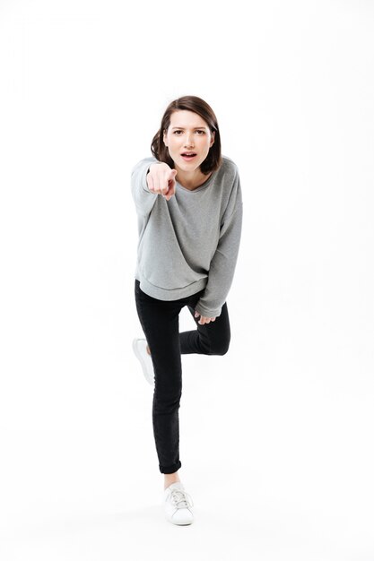 Full length portrait of a young casual woman standing on one hand and pointing finger