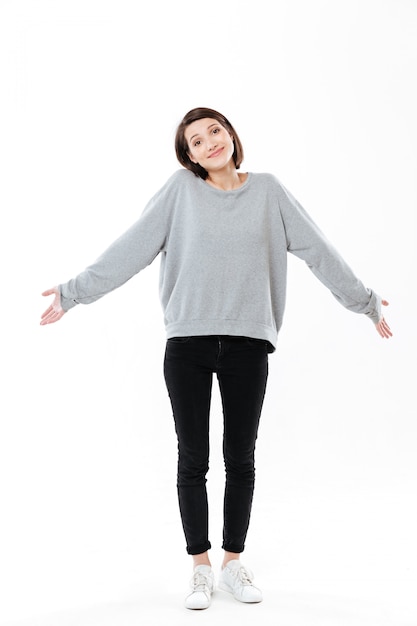 Free photo full length portrait of a young cinfused woman shrugging shoulders