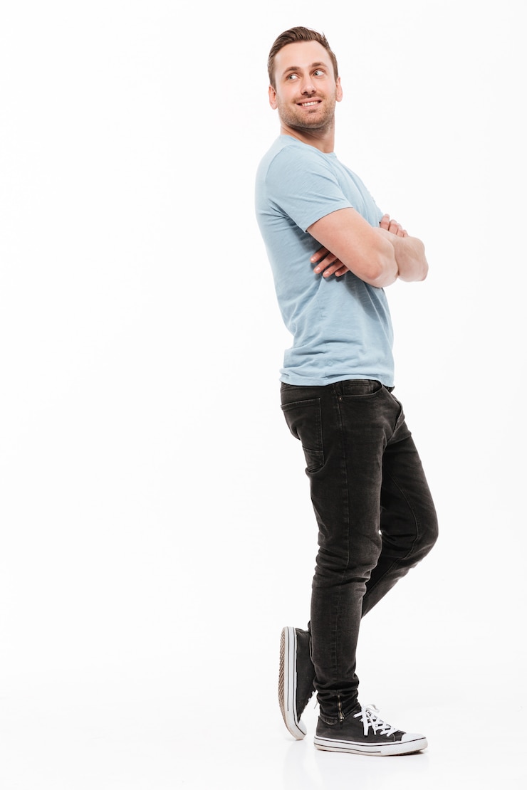 Free Photo full-length portrait of young man in casual posing with broad smile and arms folded, looking backward