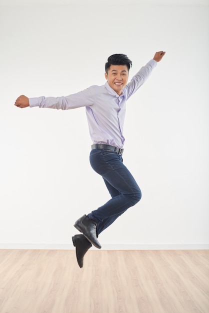 Full length portrait of young man jumping full of happiness