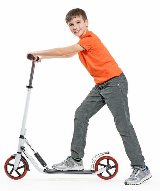 Full length profile of a happy kid riding a scooter isolated on white background