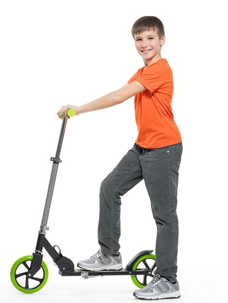 Full length profile of a happy kid with a scooter isolated on white background