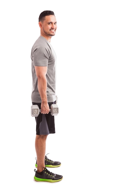 Full length profile view of a Latin man working out with a couple of dumbbells and smiling