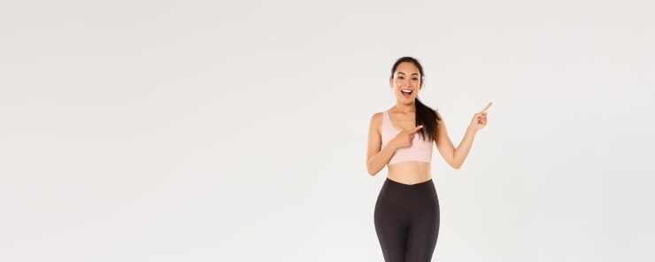 Free Photo full length of sassy attractive female athelte asian fitness girl in sportswear pointing fingers upp