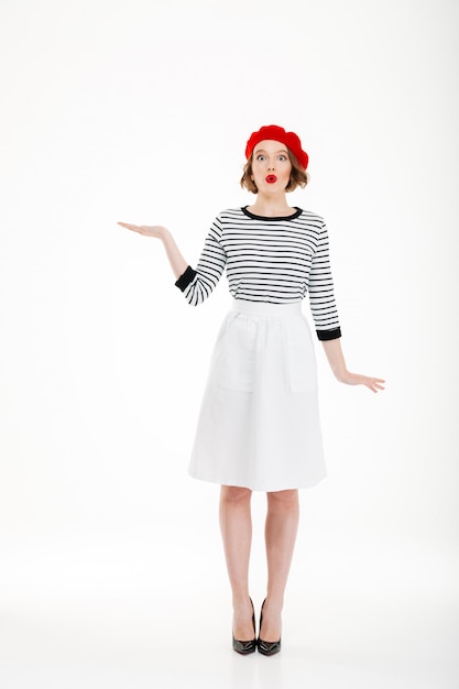 Full-length shot of amazed young woman looking camera and holding copy space on palm