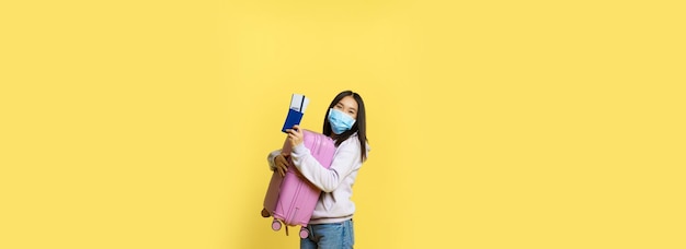 무료 사진 그녀의 가방과 여권 위트를 들고 의료 얼굴 마스크에 전체 길이 샷 귀여운 한국 소녀 관광