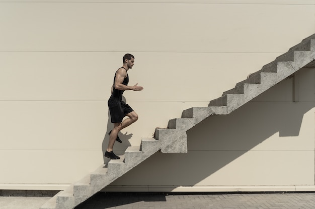 階段に上る健康的な運動男性の完全な長さのショット。
