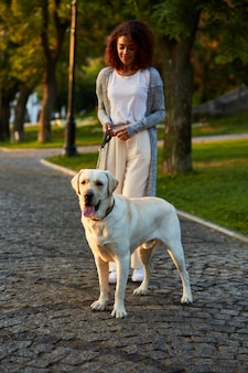 犬​と​一緒​に​公園​で​朝​歩いている​かなり​健康な​若い​女性​の​全身​ショット