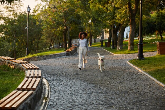 강아지와 함께 공원에서 아침에 걷는 꽤 건강한 젊은 아가씨의 전체 길이 샷