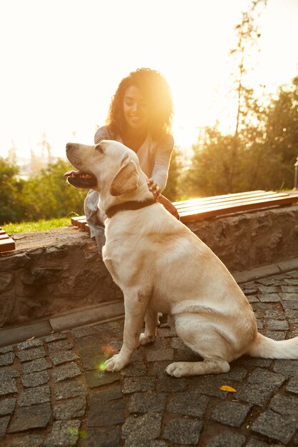 Full-length shot of pretty white dog with owner in park walking