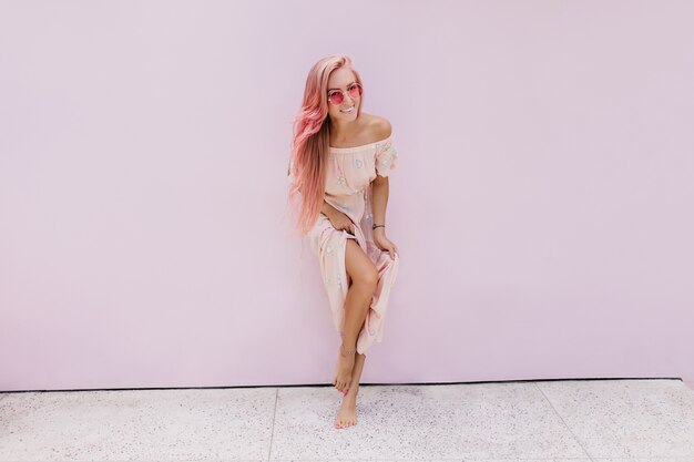 Снимок романтичной женщины с розовыми волосами в полный рост во время фотосессии.