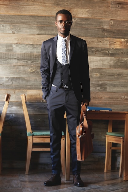 Full-length shot of successful African entrepreneur in formal wear, holding briefcase