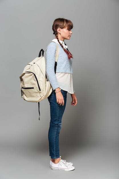 Full length side view portrait of a pretty schoolgirl