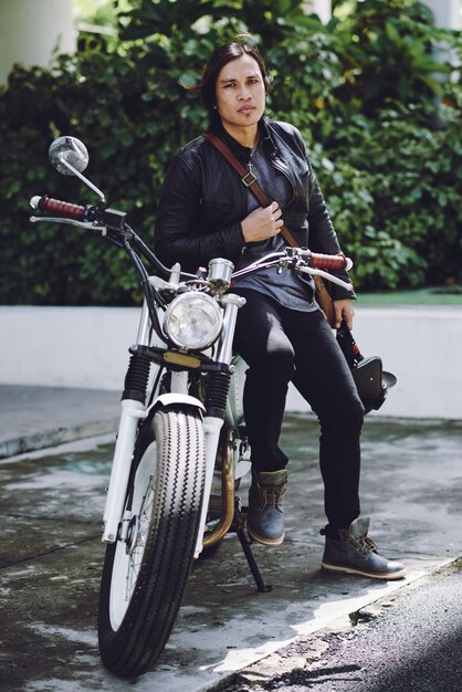 Full-length view of biker leaning on his motorcycle 