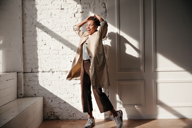 Free photo full length view of ecstatic woman in trench coat