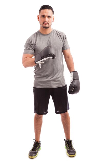 Вид в полный рост на сильного боксера в перчатках, показывающего его мышцы перед боем
