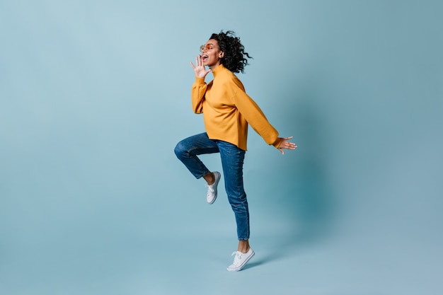 Full length view of woman jumping on blue wall