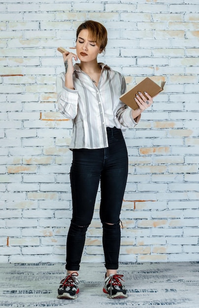 Full length young girl holding book and eating cookie High quality photo