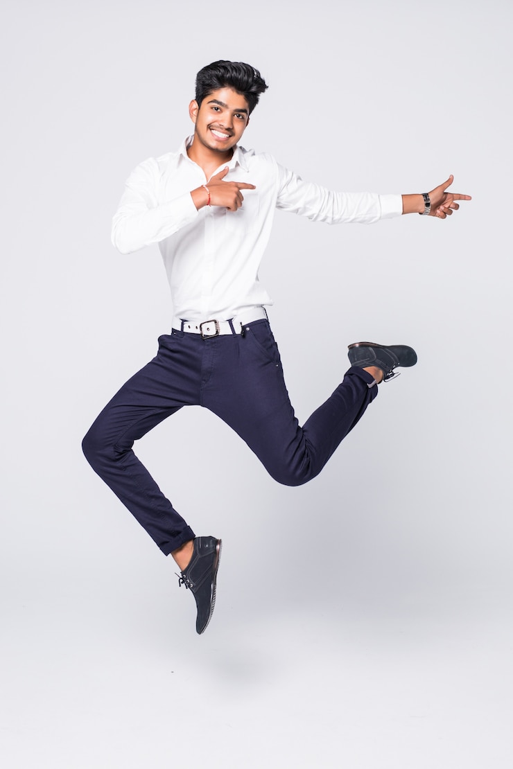 Free Photo full length of young man cheering and jumping over white wall
