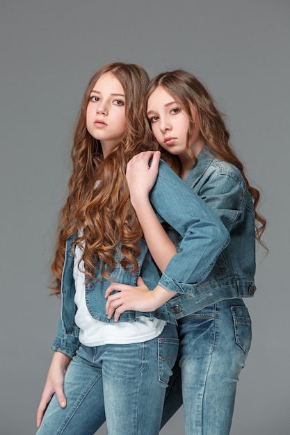 Full length of young slim female girl in denim jeans on gray background