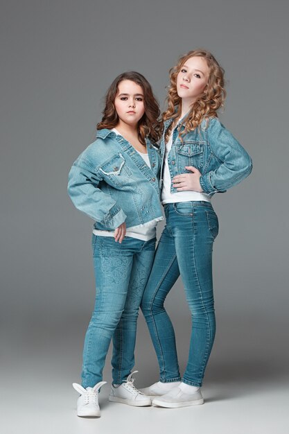 Full length of young slim female girl in denim jeans on gray background