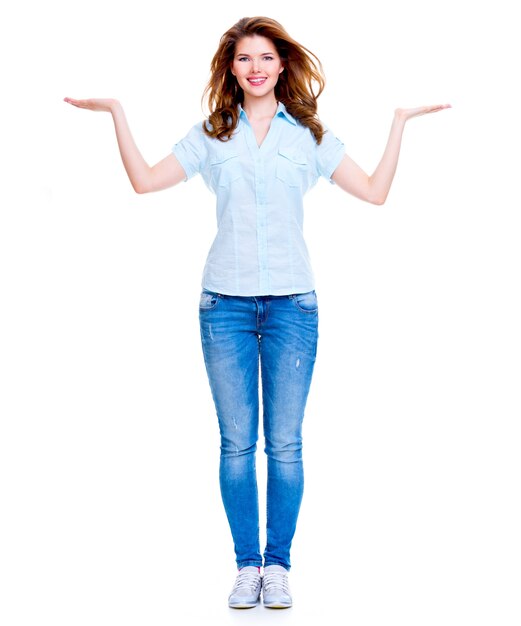 Полный портрет счастливой женщины с жестом представления над белой предпосылкой.