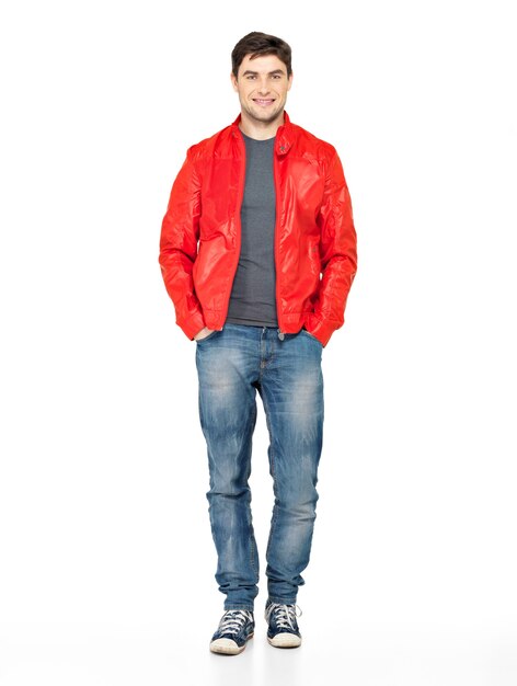 Full portrait of smiling happy handsome man in red jacket, blue jeans and gymshoes. Beautiful guy standing isolated on white