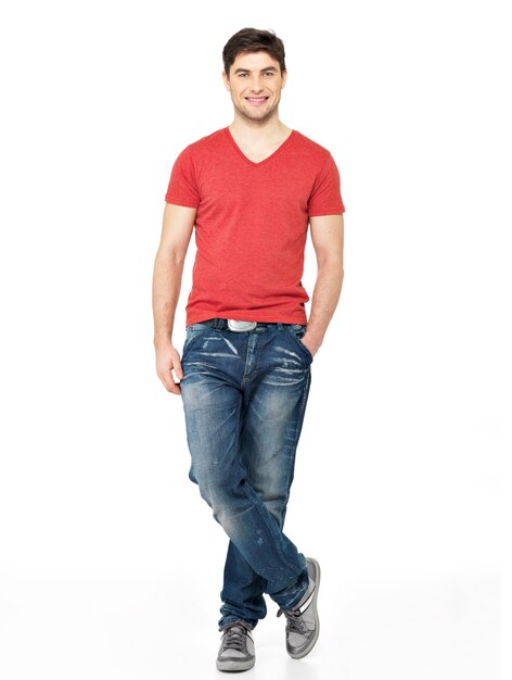 白い背景で隔離の赤いTシャツカジュアルで笑顔の幸せなハンサムな男の完全な肖像画。ポーズの美しい若い男