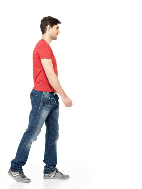 Full portrait of smiling  walking man in red t-shirt casuals  isolated on white wall.