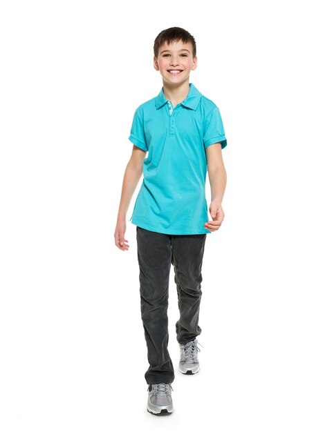 Полный портрет улыбающегося идущего мальчика-подростка в синей футболке вскользь, изолированных на белом.