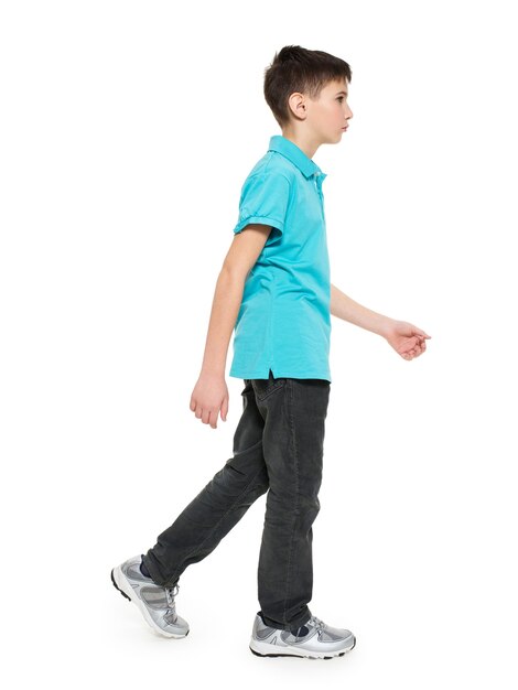 Полный портрет ходьбы подростка мальчика в синей футболке вскользь, изолированных на белом.