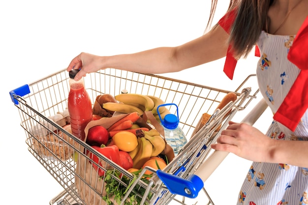Full shopping cart at store with fresh vegetables and hands close-up, isolated on white background