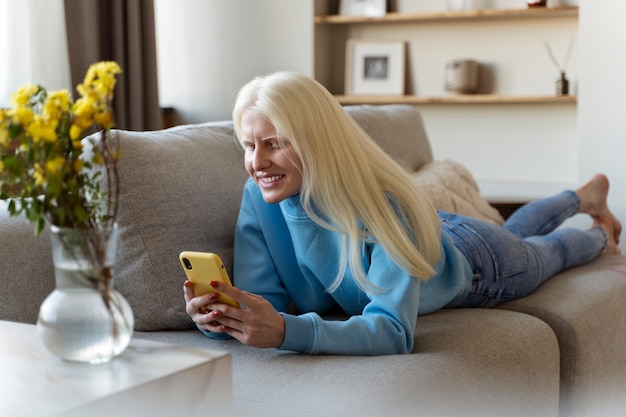 Full shot albino woman holding smartphone