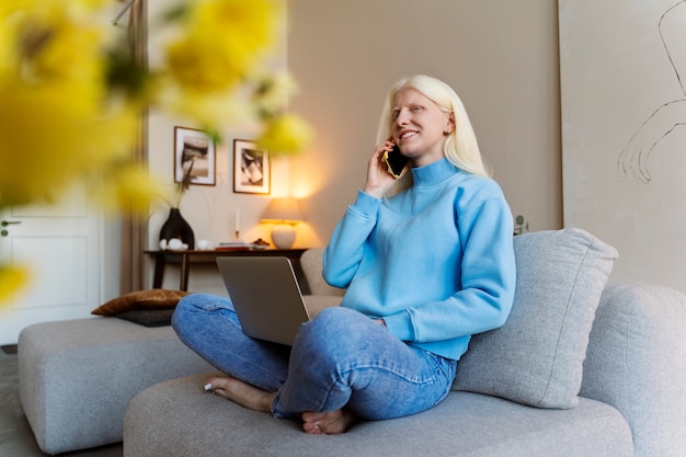 Free photo full shot albino woman holding smartphone