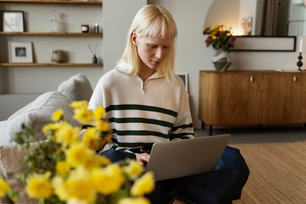 Full shot albino woman working on laptop