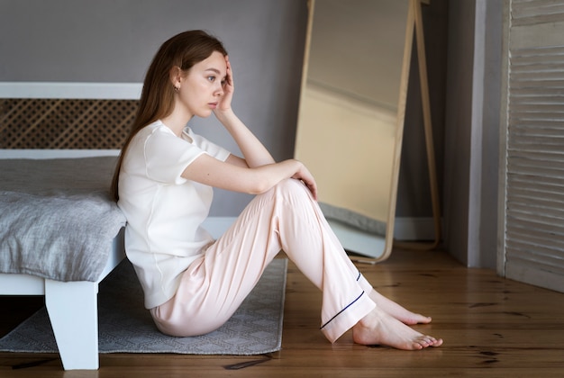 Full shot anxious woman sitting on floor