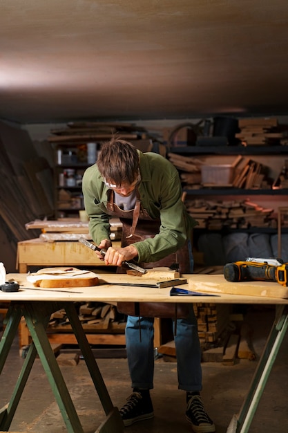 Artigiano a figura intera che fa il taglio del legno