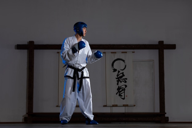 Foto gratuita uomo asiatico del colpo pieno che pratica taekwondo