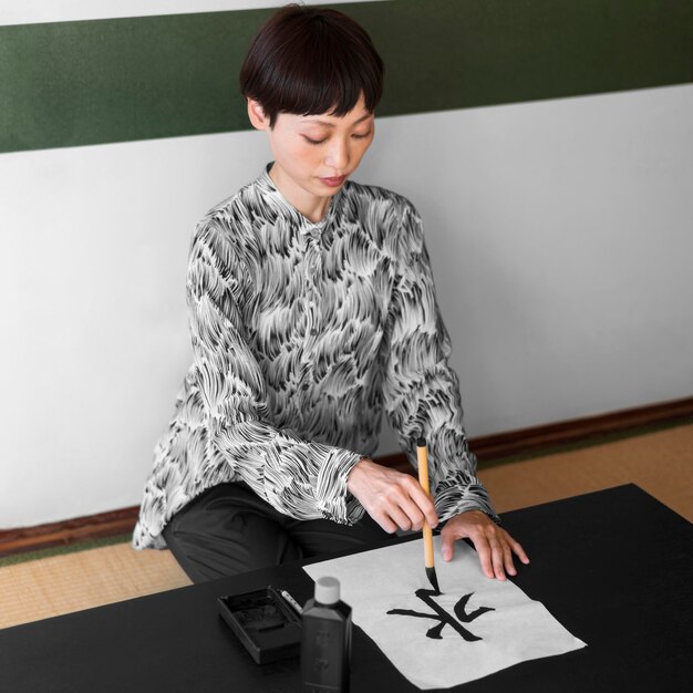 Full shot asian woman painting letter