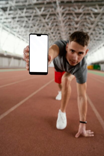 Full shot athlete holding smartphone