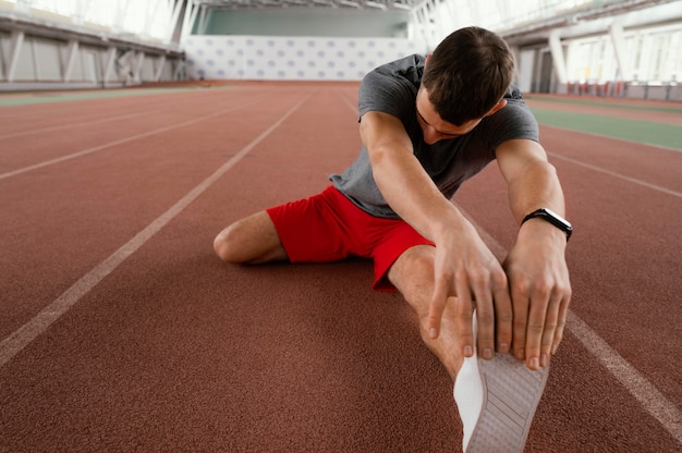 Full shot athlete stretching leg