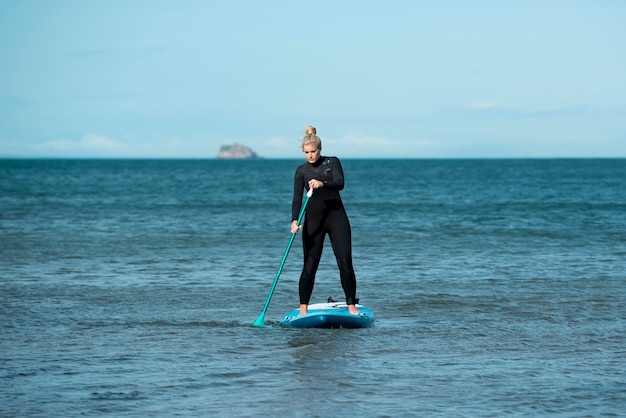 Full shot athletic woman paddleboarding