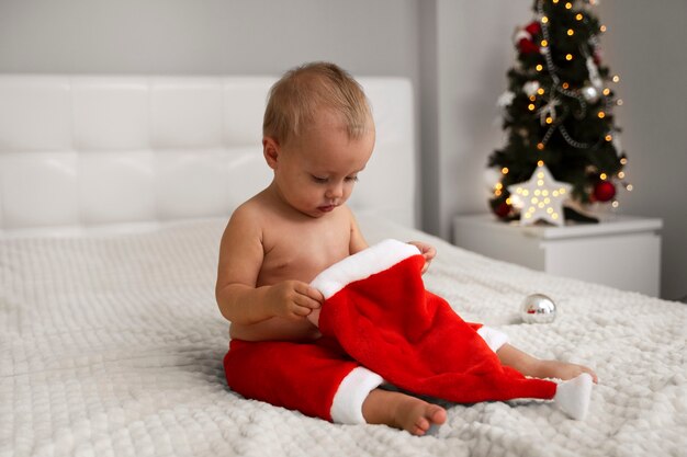 Free photo full shot baby holding santa hat