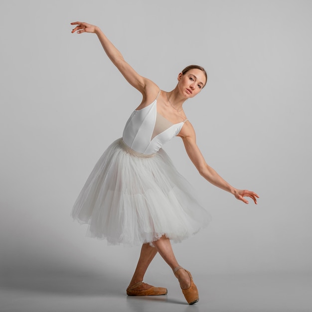 Full shot ballerina posing with pointe shoes