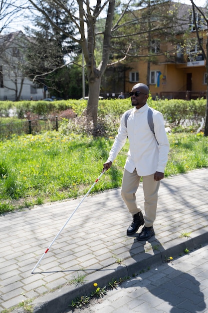 Full shot blind man walking with white cane