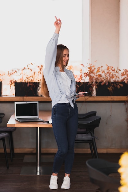 Ragazza bionda della foto a figura intera che solleva la sua mano