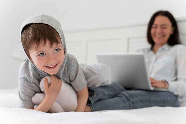 Free photo full shot blurry mother and kid in bed