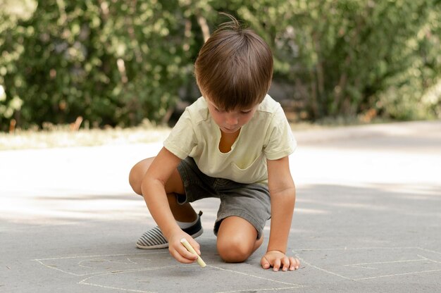 full shot boy drawing on ground