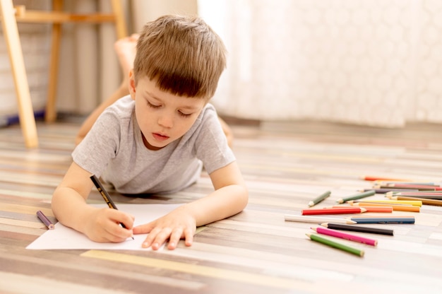 Free photo full shot boy on floor drawing